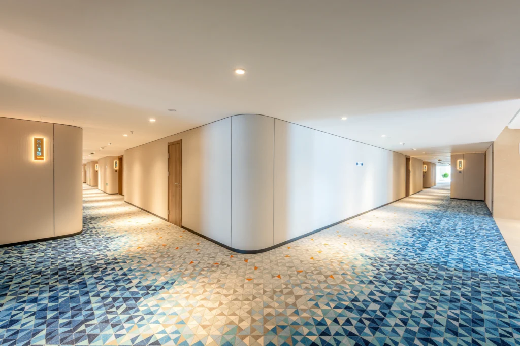 Bespoke decorative hotel wall cladding in corridor with curved panels wood doors patterned carpet lighting